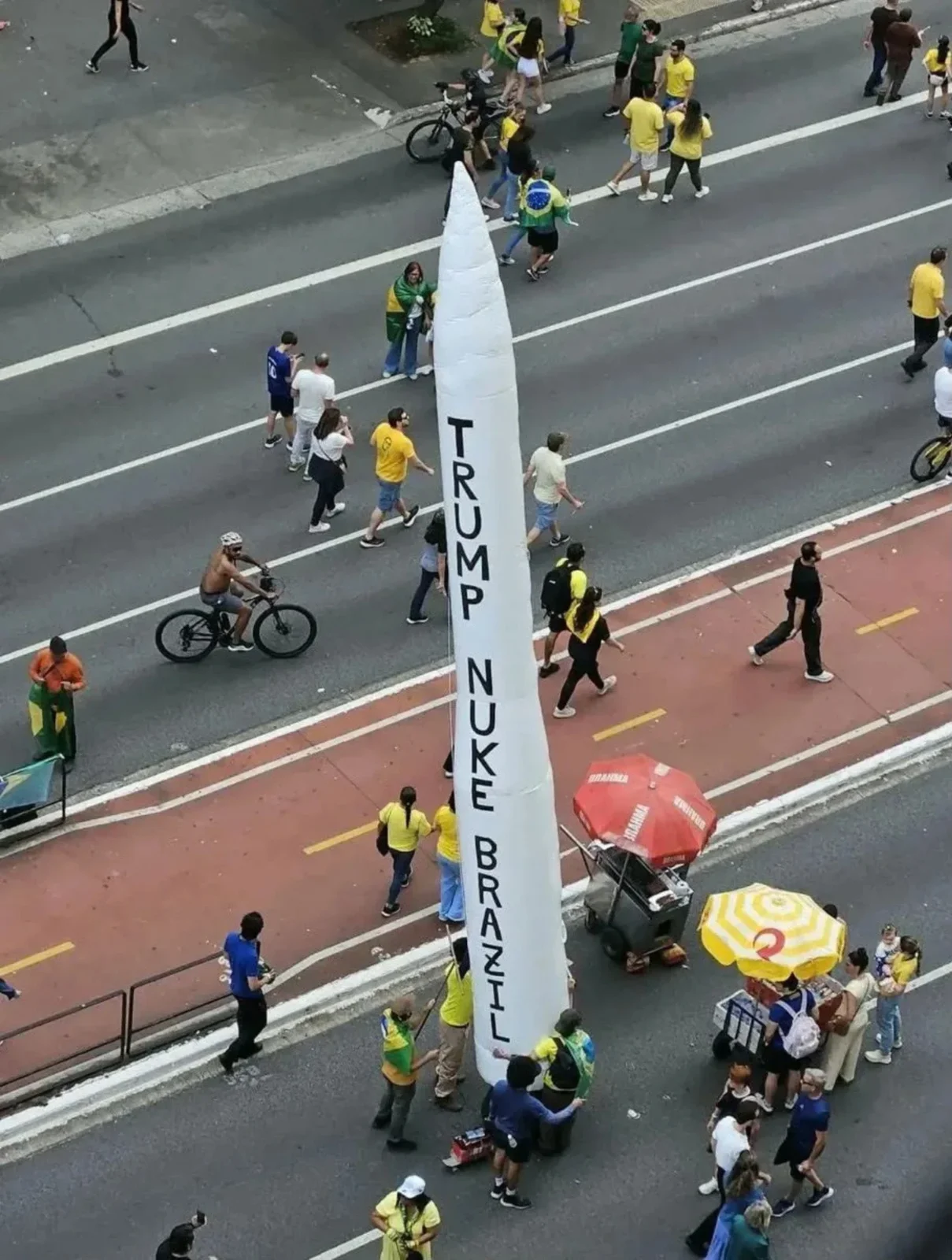 Míssil inflável branco com a inscrição Trump nuke Brazil erguido em meio a manifestantes na Avenida Paulista